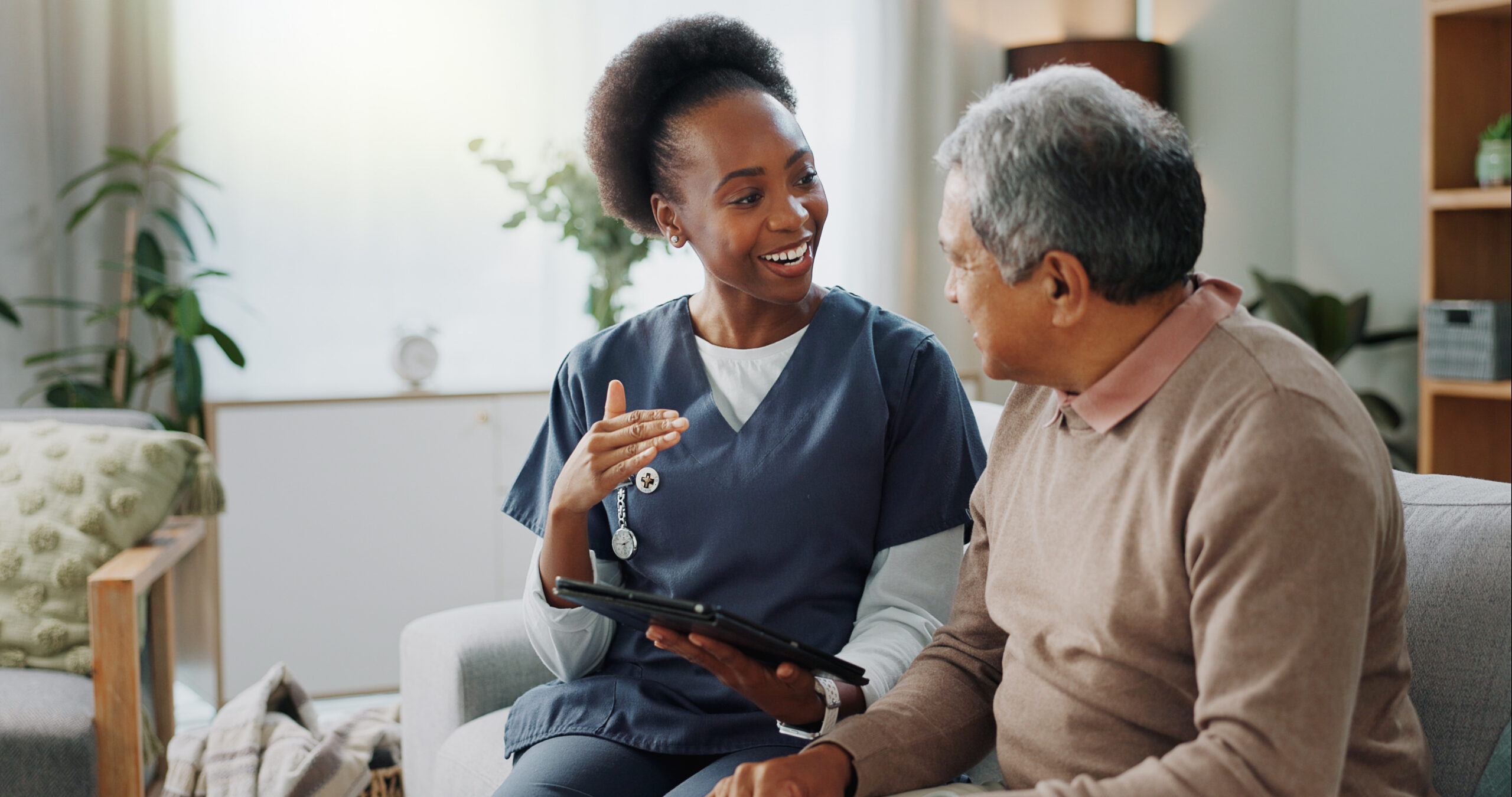 A clinician talks with an older patient during a home visit.